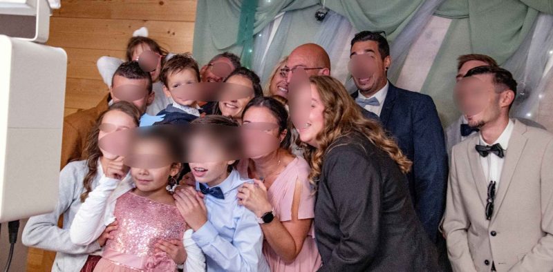 Groupe d’invités réunis autour d’une borne photo lors de la soirée de mariage, sourires joyeux et tenues élégantes.
