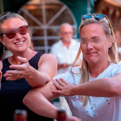 Deux invitées rient et dansent en pleine réception de mariage en extérieur, dans une ambiance joyeuse et détendue.